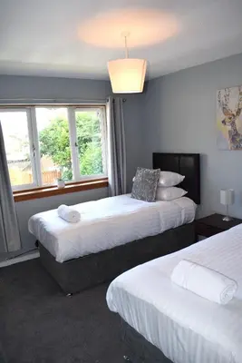 a hotel room with two beds and a window at Kelpies Serviced Apartments- Jamieson in Stenhousemuir
