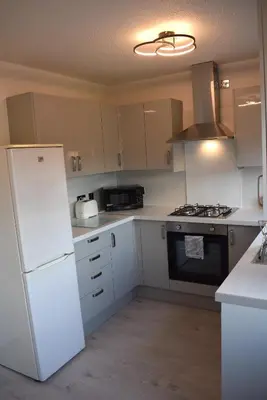 a kitchen with white appliances and a white refrigerator at Kelpies Serviced Apartments- Jamieson in Stenhousemuir