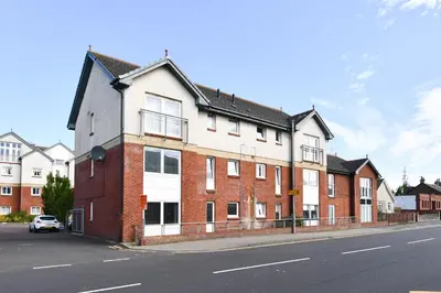 a large brick building on the side of a street at Troon Executive Apartment in Troon