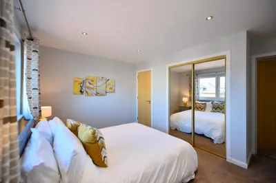 a bedroom with a bed and a mirror at Troon Executive Apartment in Troon