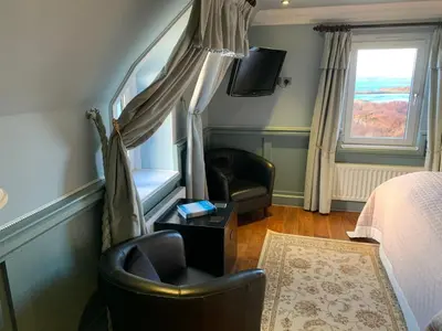 a bedroom with a bed and a chair and a window at Corrie House in Craobh Haven