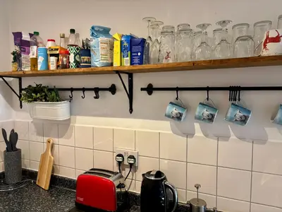 a kitchen with a counter top with glasses on a shelf at Bread street, Central and spacious one bed flat in Edinburgh