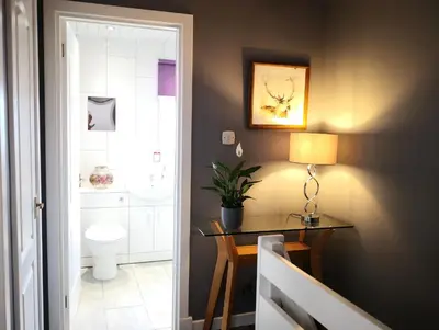 a bathroom with a table and a toilet and a lamp at Iona in Stirling