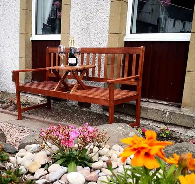 a wooden bench with a table and two glasses of wine at Iona in Stirling