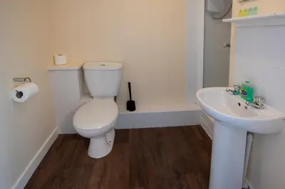 a white bathroom with a toilet and a sink at Irvine Riverside Guesthouse in Irvine