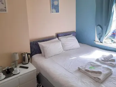 a bed with white sheets and a blue wall at Irvine Riverside Guesthouse in Irvine