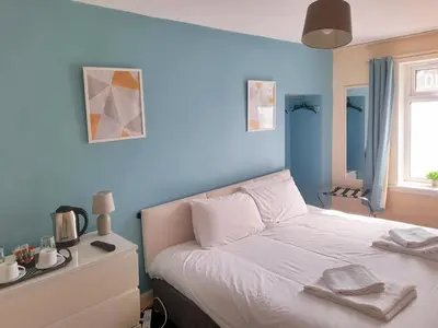 a bedroom with a white bed with a blue wall at Irvine Riverside Guesthouse in Irvine
