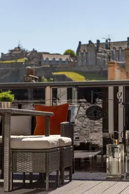 a patio with a table and chairs on a balcony at The Edinburgh Rooftop Terrace in Edinburgh