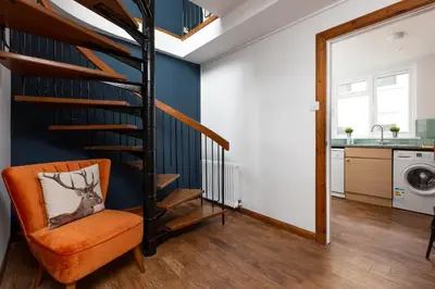 an orange chair in a living room with a spiral staircase at The Edinburgh Rooftop Terrace in Edinburgh