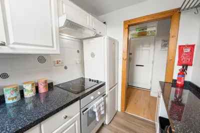 a kitchen with white cabinets and a black counter top at Charming Apt nr Centre - Terrace & Street Parking in Oban