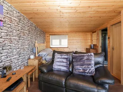 a living room with a leather couch and a bed at Blackbrae Cabin in Coatbridge