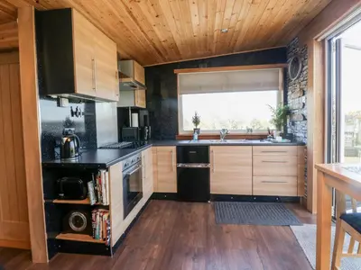 a kitchen with wooden cabinets and a large window at Blackbrae Cabin in Coatbridge