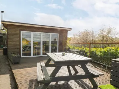 a picnic table and two chairs on a wooden deck at Blackbrae Cabin in Coatbridge