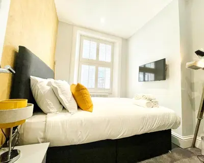 a bedroom with a bed with white sheets and yellow pillows at Gorgeous 2BR & Central Edinburgh Bolt-hole in Edinburgh
