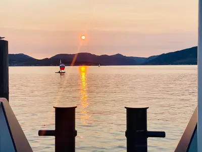 a sunset on a lake with a boat in the water at The Sleeping Lion - Dunoon Holiday Home in Dunoon