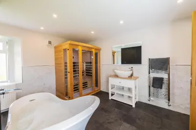 a bathroom with a white tub and a sink at Nether Newton - Sleeps 12, Hottub, Sauna, Private Garden in Newmilns