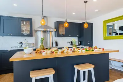 a kitchen with blue cabinets and a wooden counter top at Nether Newton - Sleeps 12, Hottub, Sauna, Private Garden in Newmilns