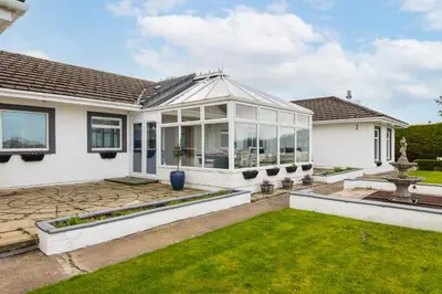 a home with a conservatory and a lawn at Alton Villa, Sleeps 12, Great for Families, Undercover Hotub & Games Room in Newmilns