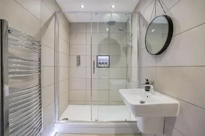 a bathroom with a shower and a sink and a mirror at Oban Bay Apartments in Oban