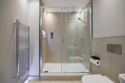 a bathroom with a shower with a tub and a toilet at Oban Bay Apartments in Oban