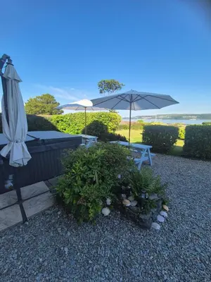 a patio with a table and an umbrella and plants at Firthview House in Kirn