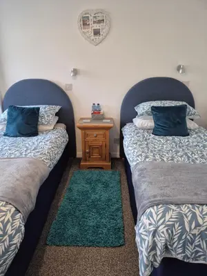 two beds in a room with a nightstand between them at Firthview House in Kirn