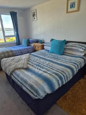 a bedroom with two beds with blue pillows and a window at Firthview House in Kirn