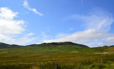 a green field with a mountain in the background at Corriemuckloch Unique Huts in Dunkeld