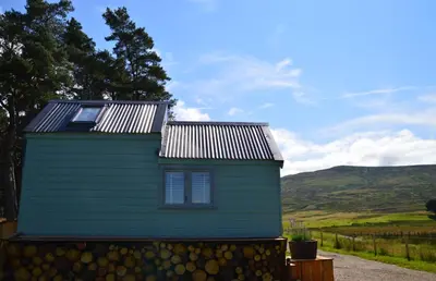 a green house with a solar roof on a hill at Corriemuckloch Unique Huts in Dunkeld