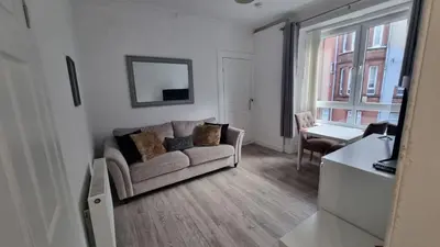 a living room with a couch and a table at Carrick - One Bed Apartment in Largs