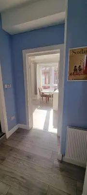 a room with blue walls and a dining room with a table at Carrick - One Bed Apartment in Largs