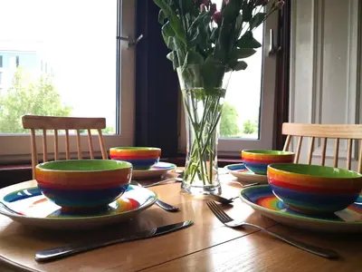 a wooden table with plates and a vase with flowers at Forth View Apartment in Stirling