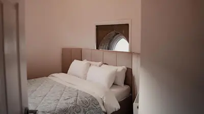 a bedroom with a bed with white pillows and a mirror at Royal Chambers Serviced Apartments in Glasgow