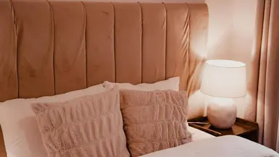 a bed with a brown headboard with a lamp and pillows at Royal Chambers Serviced Apartments in Glasgow
