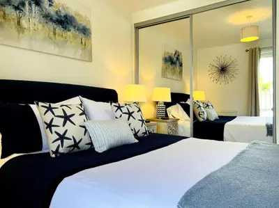 a bedroom with a bed with pillows and a mirror at Riverside View Apartment in Balloch, Loch Lomond in Balloch