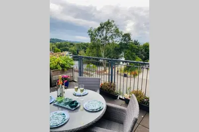 a table with plates on it on a balcony at Riverside View Apartment in Balloch, Loch Lomond in Balloch