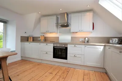 a kitchen with white cabinets and a wooden floor at Greenlea in Strachur