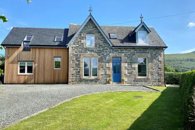 a stone house with a blue door and a yard at Greenlea in Strachur