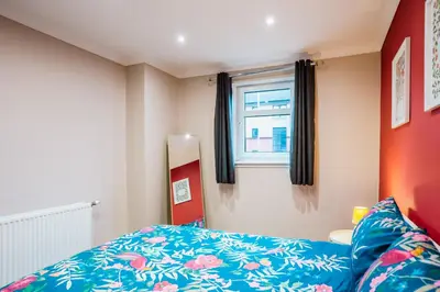 a bedroom with a blue bed and a window at Dalmarnock Stay in Glasgow