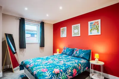 a bedroom with a bed and a red wall at Dalmarnock Stay in Glasgow