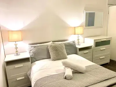 a bedroom with a bed with two lamps and a mirror at Central 1-Bed Apt Sleeps 4 5 mins to Station in Greenock