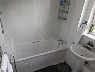 a white bathroom with a tub and a sink at Central 1-Bed Apt Sleeps 4 5 mins to Station in Greenock