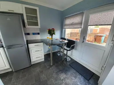 a small kitchen with a table and a refrigerator at PREMIER - Kenilworth House in Holytown