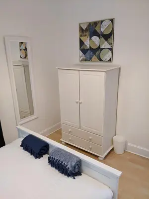 a bedroom with a white cabinet with two pillows on a bed at Glenclova - No 5 Bellyeoman, bright two bedroom apartment in Fife
