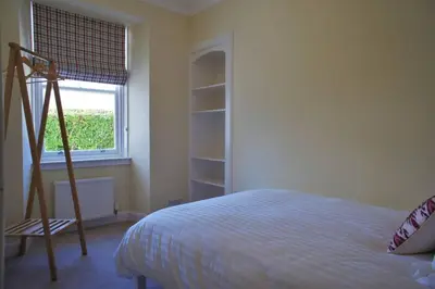 a bedroom with a bed and a ladder next to a window at 17 William Street in Helensburgh
