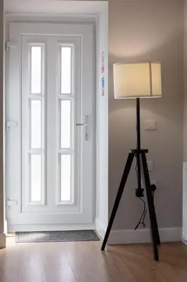 a lamp on a tripod in front of a door at Shore View - Donnini Apartments in Prestwick