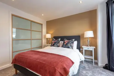 a bedroom with a large bed with a red blanket at SECC Hydro Clyde View Apartment in Glasgow