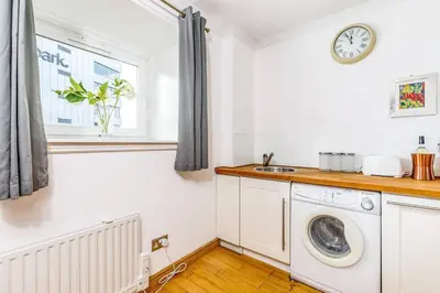 a kitchen with a washing machine and a window at Fresh, modern West End apartment beside Hydro in Glasgow