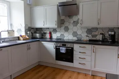 a kitchen with white cabinets and a black oven at Airds Apartments in Oban