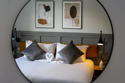 a bedroom with a bed with pillows and a mirror at Airds Apartments in Oban